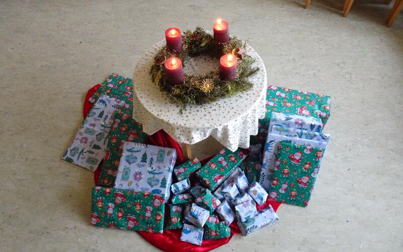 Liebevoll verpackte Weihnachtsgeschenke um einen Tisch mit Adventskranz